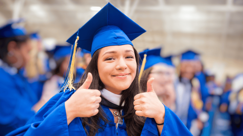 Bryan University Fall 2025 Commencement: A woman in graduation regalia smiling and giving two thumbs up