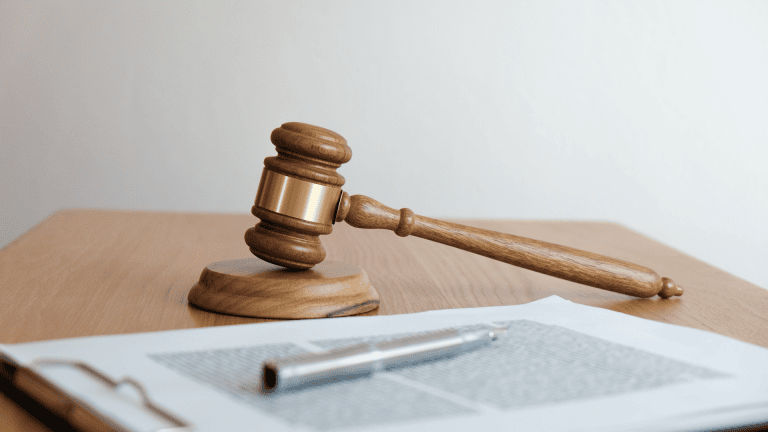 wooden gavel on a desk with papers and pen
