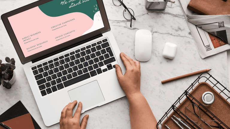 A person's hands on a laptop with a business card on it