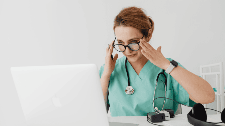 a person in scrubs sitting in front of a laptop