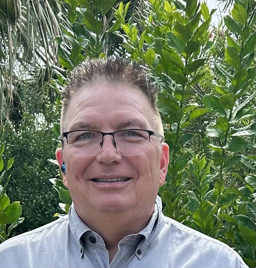 A smiling man in front of a tree