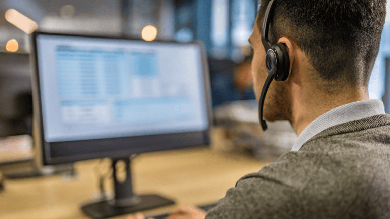 A man working on a computer with a headset on