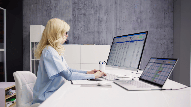 A medical billing and coding professional sits at a desk in front of a computer