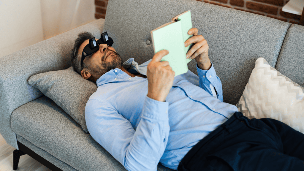 A person is reading a book while laying on a couch