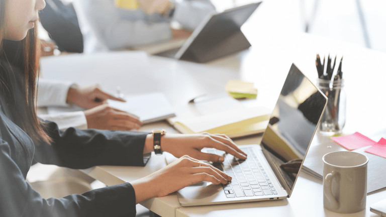 a person is typing on a laptop in an office