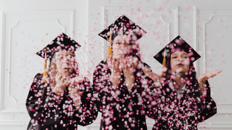three individuals in graduation gowns throwing confetti
