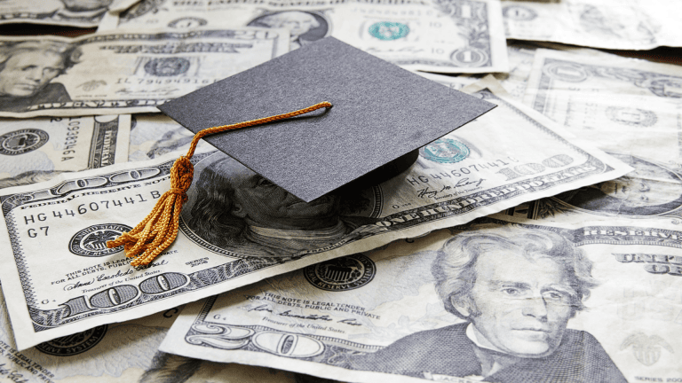 a graduation cap sits on top of a pile of money
